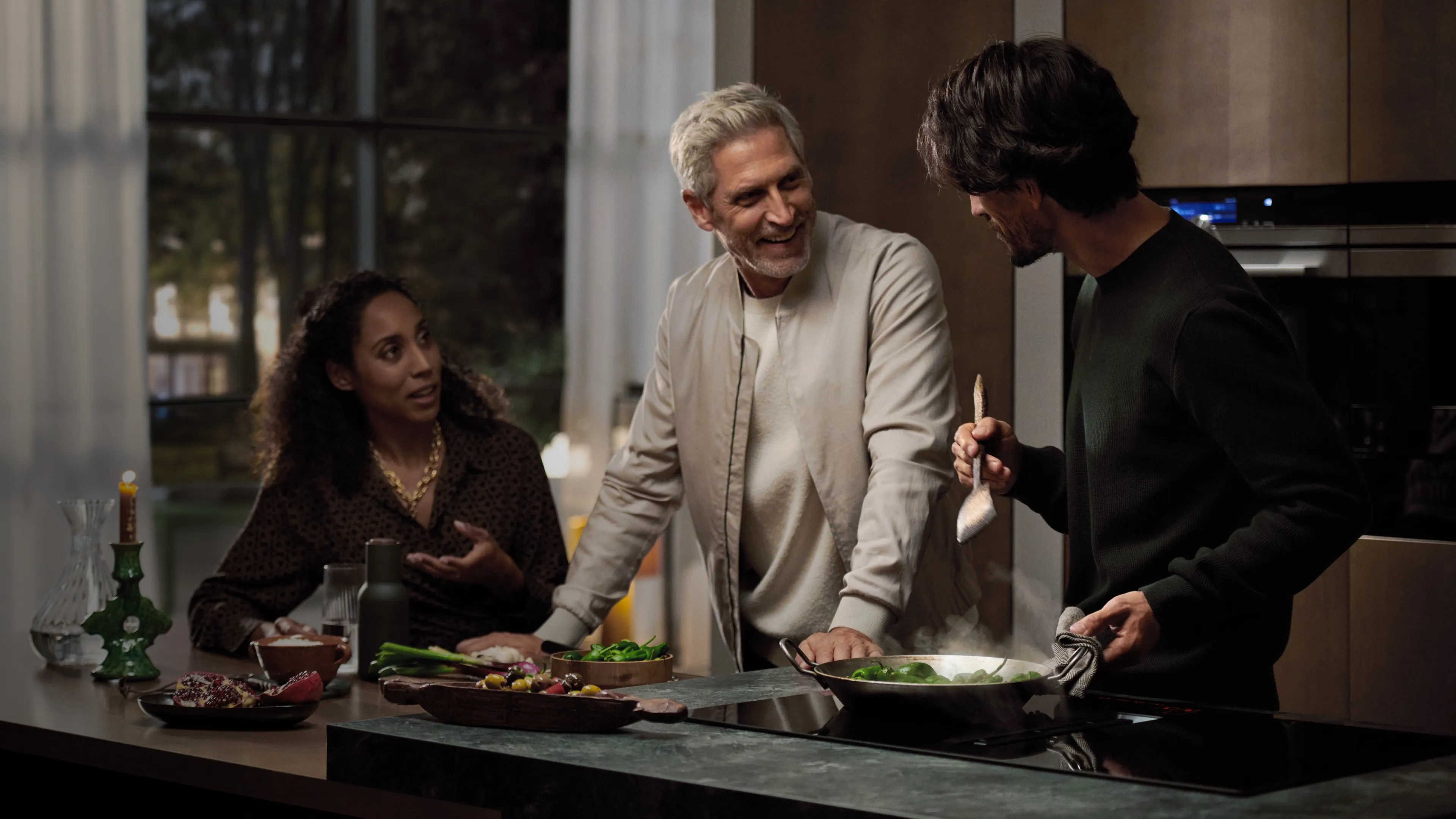 Three people preparing food together in a kitchen.