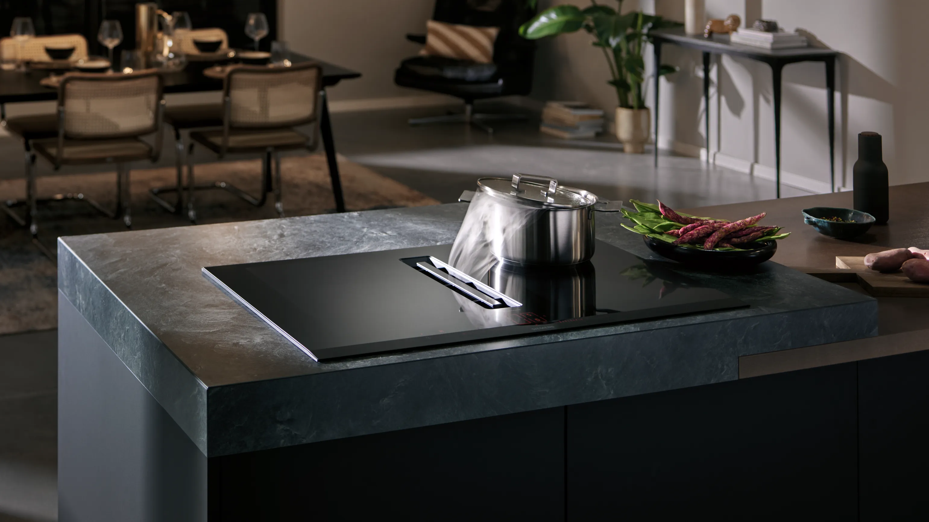 Modern kitchen countertop with induction cooktop, pots, and fresh produce.