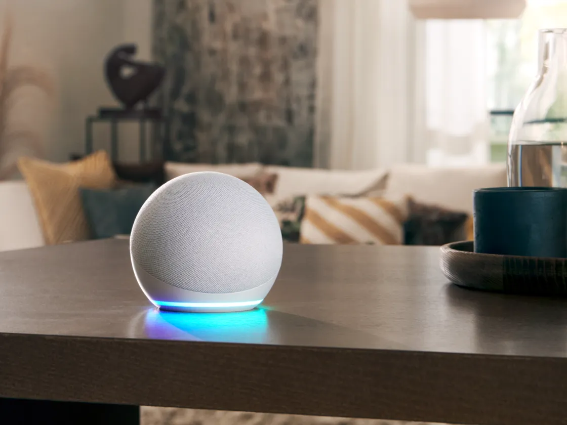Minimalist home decor with smart speaker, wooden table, and cozy living room in background.