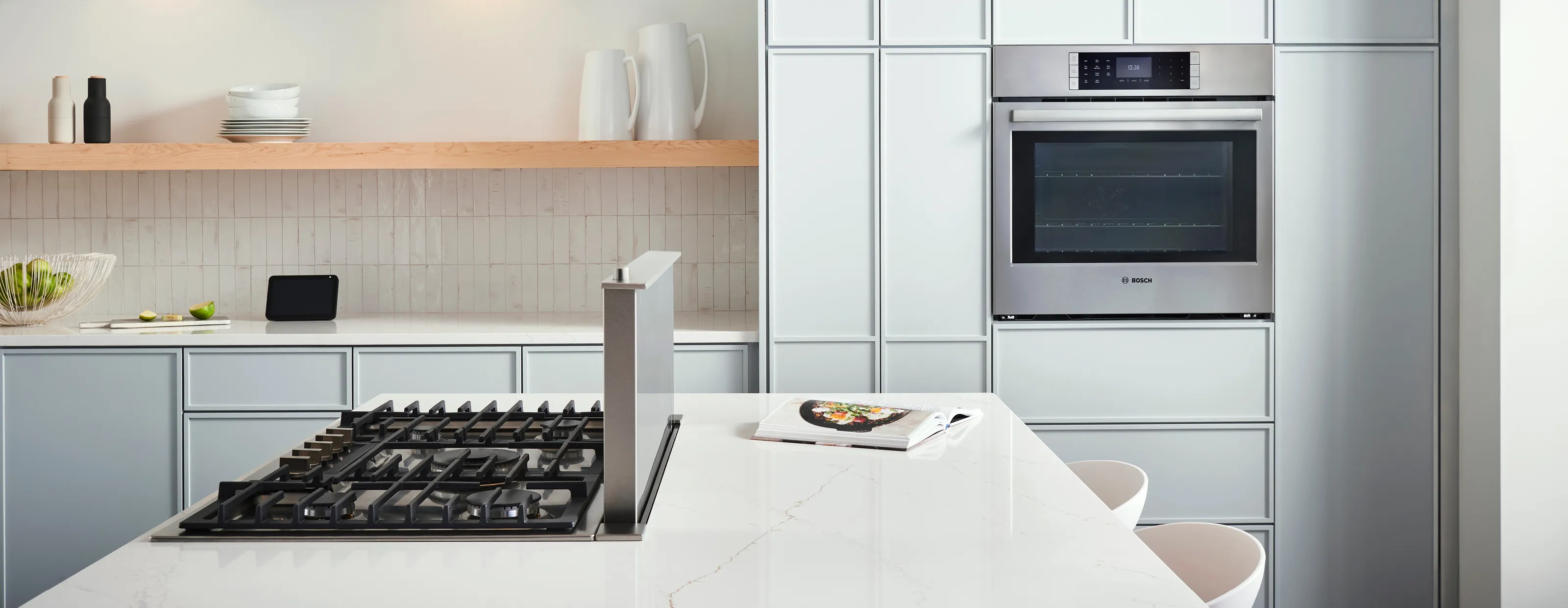 Modern kitchen with Bosch oven, gas cooktop, marble countertop and minimalist shelving.