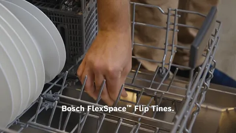 Dishwasher interior with Bosch FlexSpace Flip Tines feature, hand reaching into the appliance.