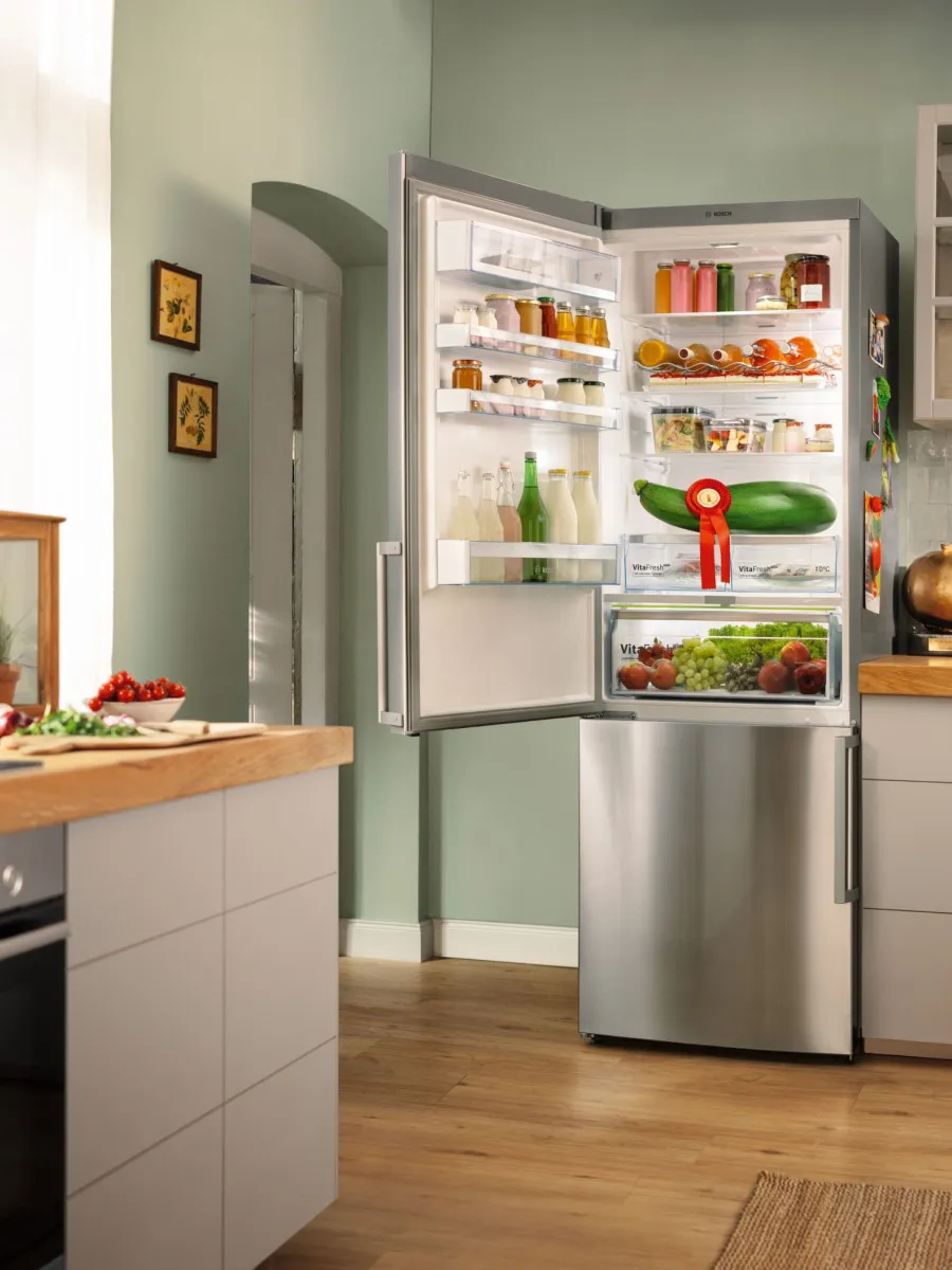 Open koelkast in moderne keuken met diverse voedingsmiddelen en planken.