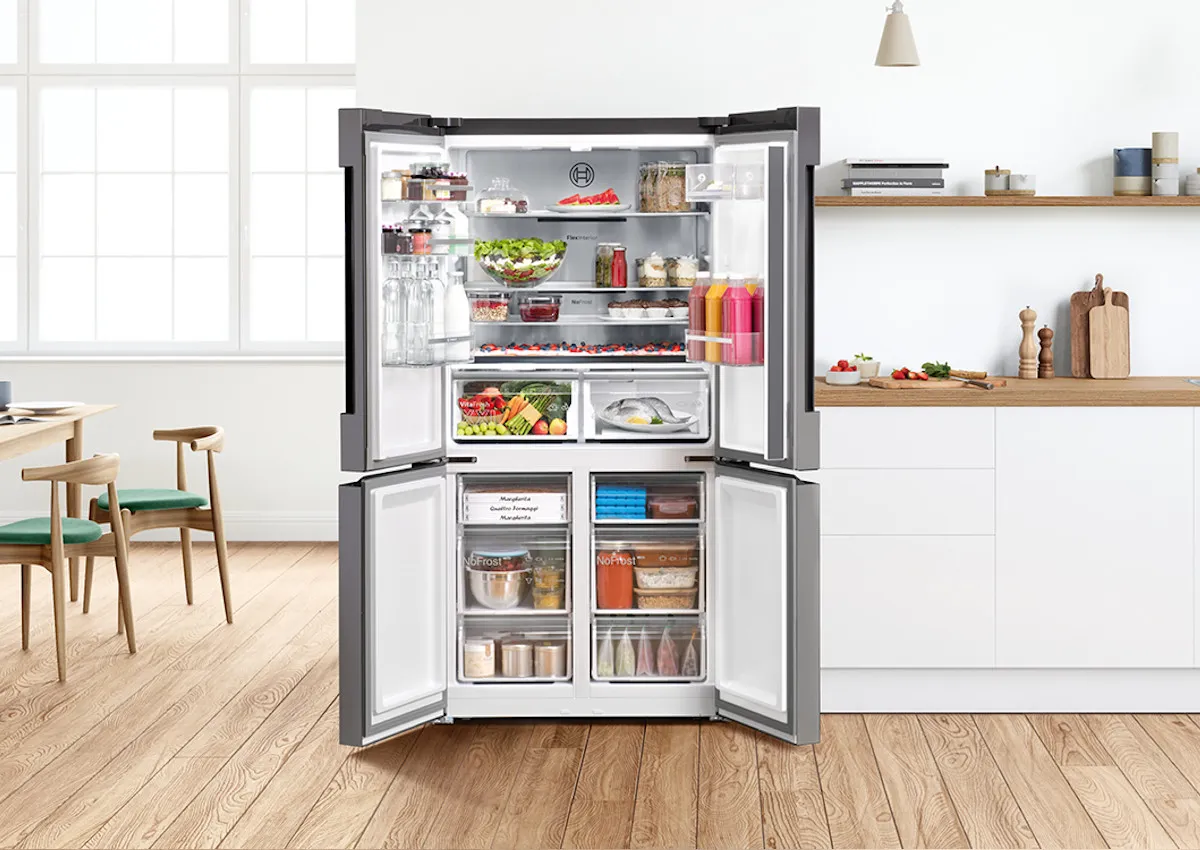 Amplia nevera moderna con varios alimentos y electrodomésticos de cocina en una cocina luminosa y aireada.