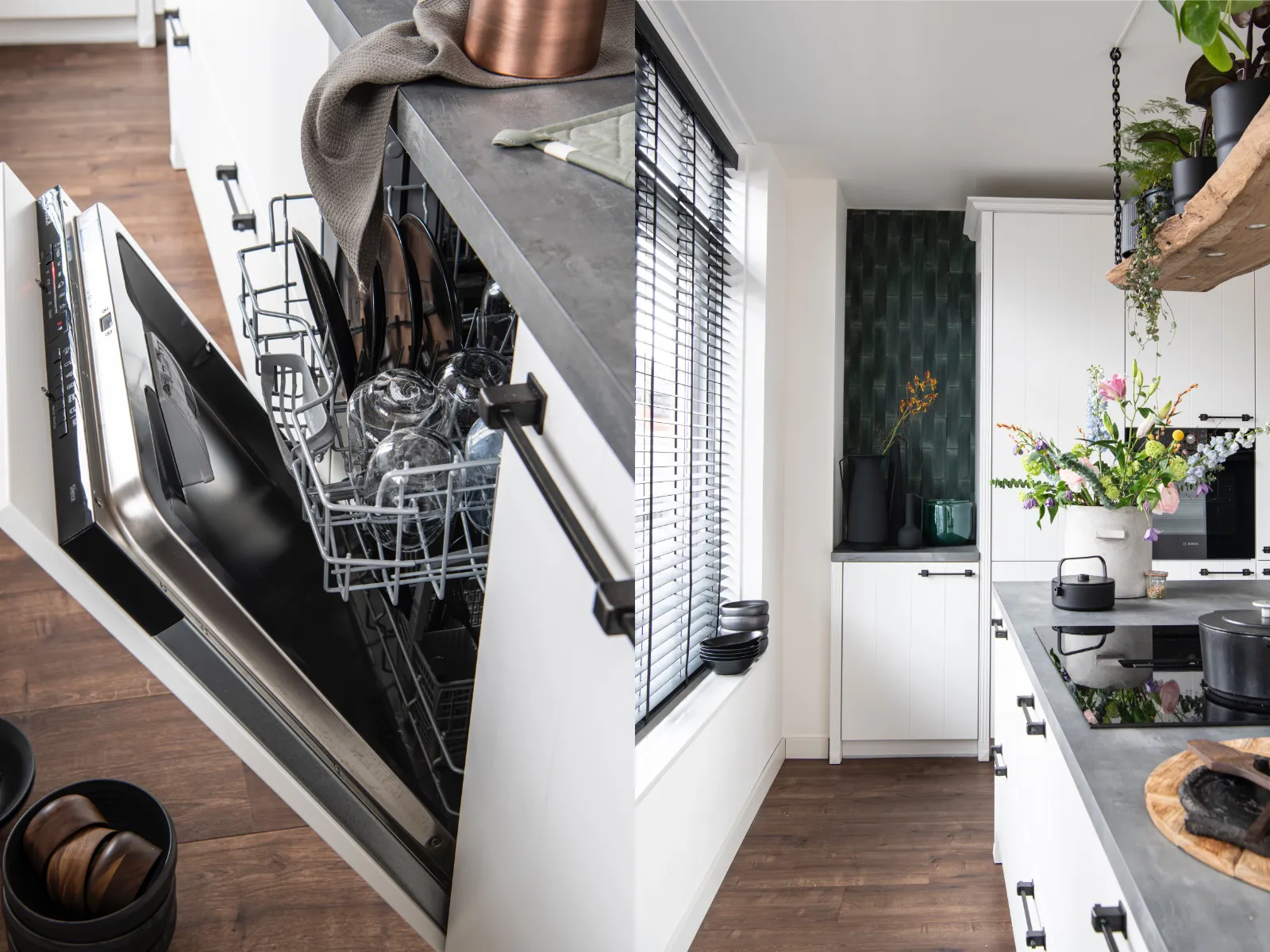 Cuisine moderne avec lave-vaisselle ouvert, ustensiles de cuisine et plantes décoratives.