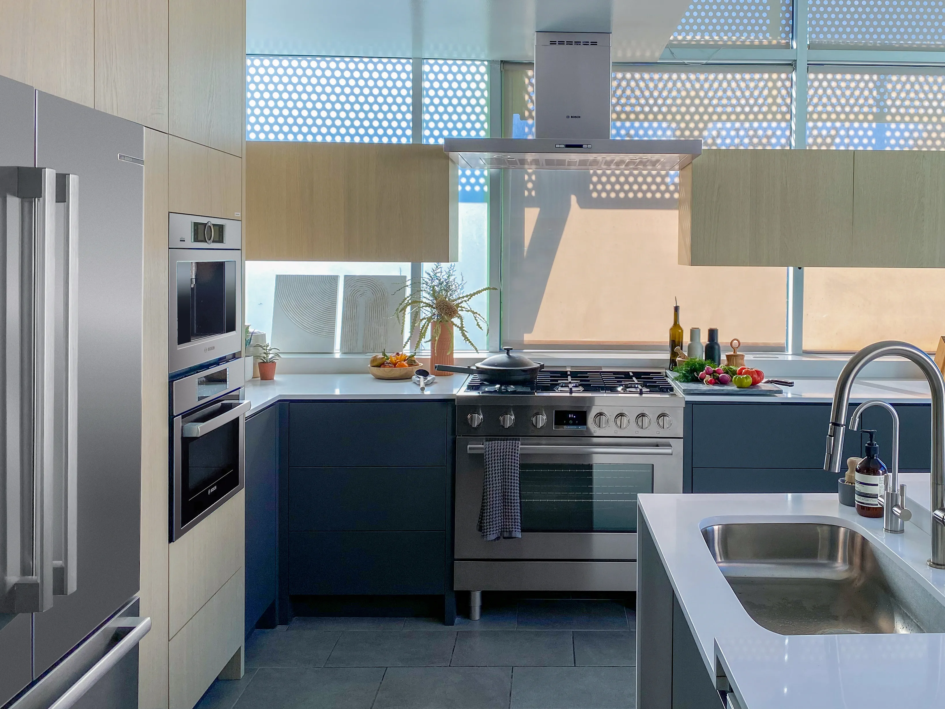 Modern kitchen with Bosch stainless steel appliances, island sink, and large windows.