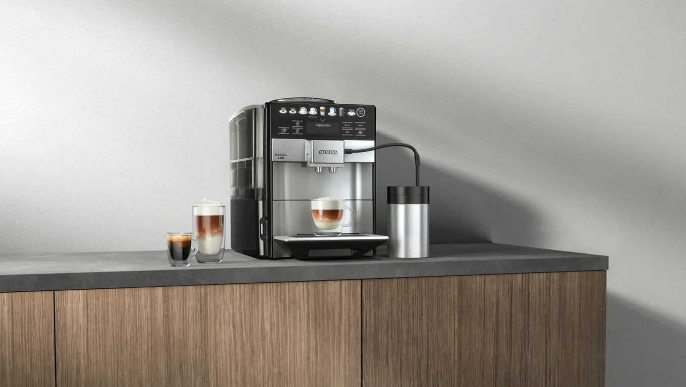 A sleek coffee machine on a modern kitchen countertop, with freshly brewed espresso and a stainless steel tumbler beside it.