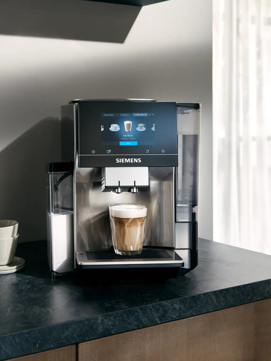 Sleek Siemens coffee machine with touchscreen interface, dispensing a latte on a dark countertop.