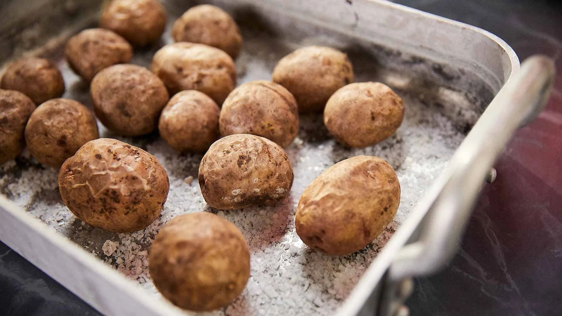 Baked potato balls on a baking tray, coated in seasoning and ready to be served.