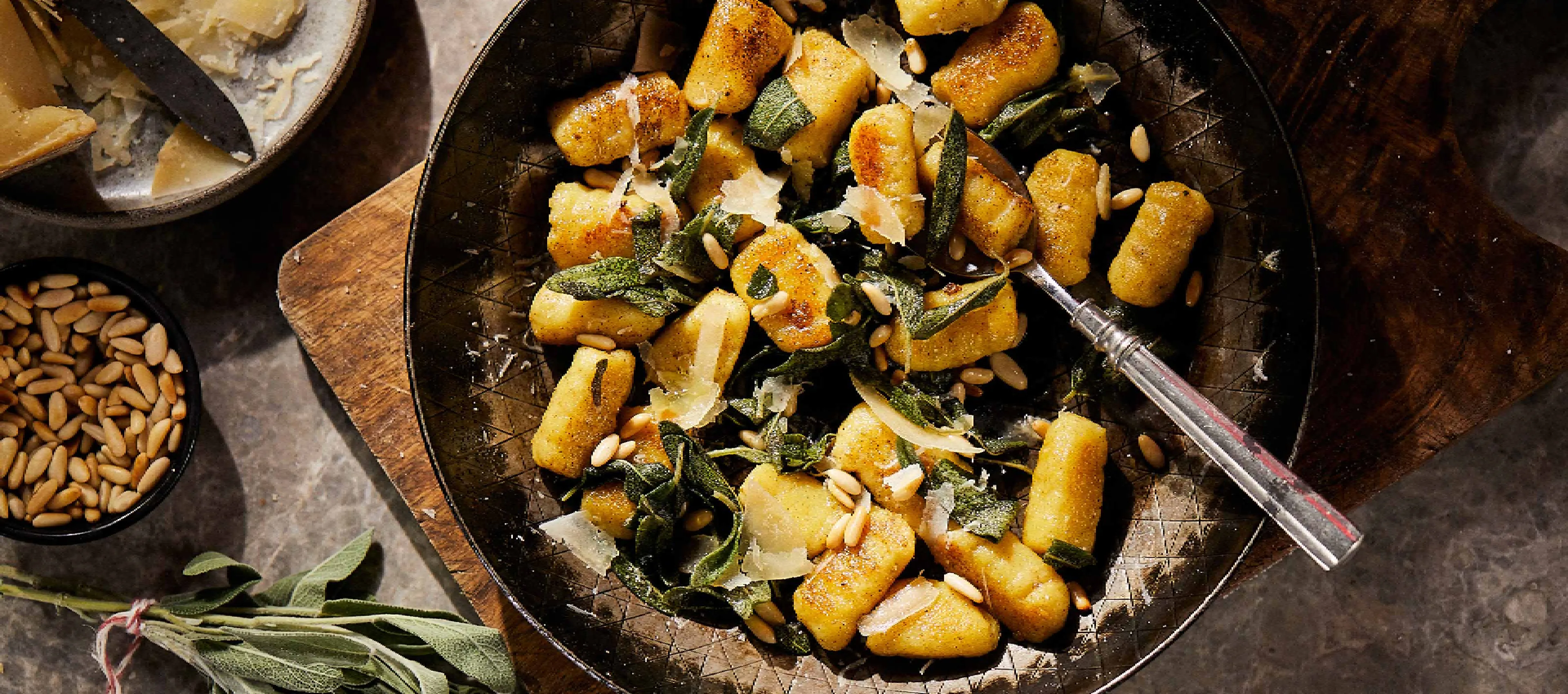 Rustic dish with roasted potatoes, herbs, and nuts on a wooden table.