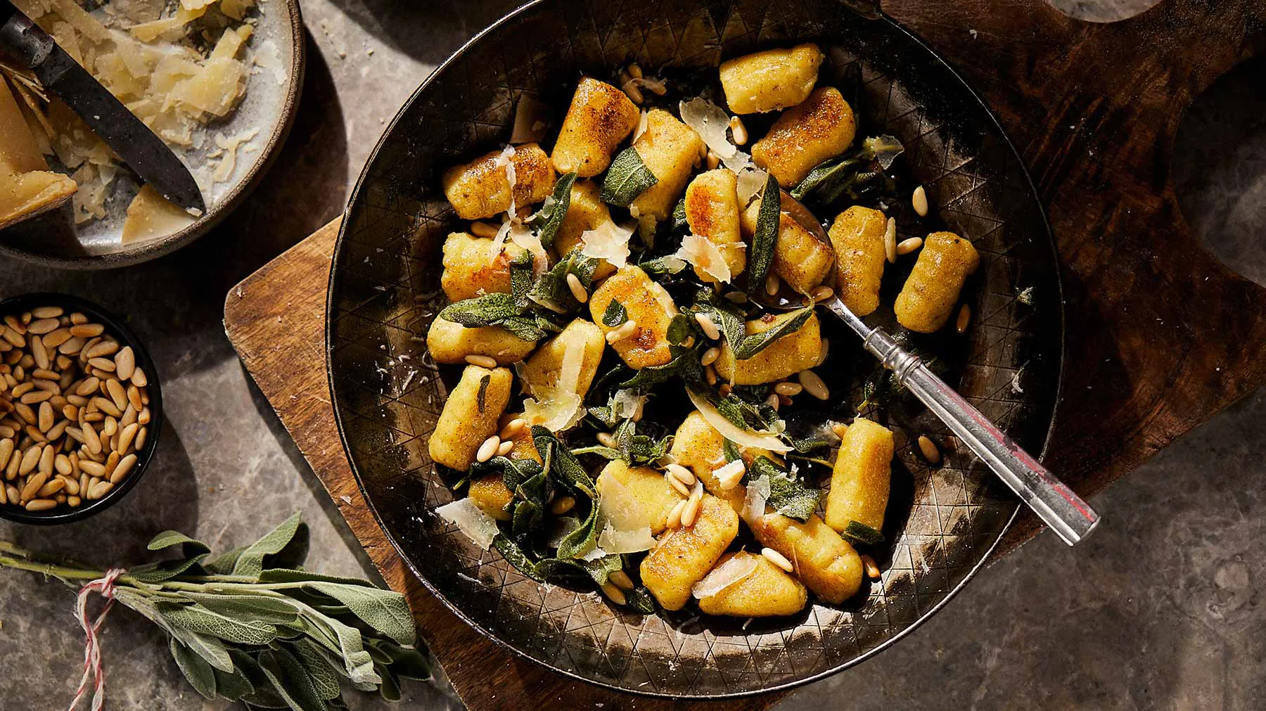 Rustic dish with roasted potatoes, herbs, and nuts on a dark background.
