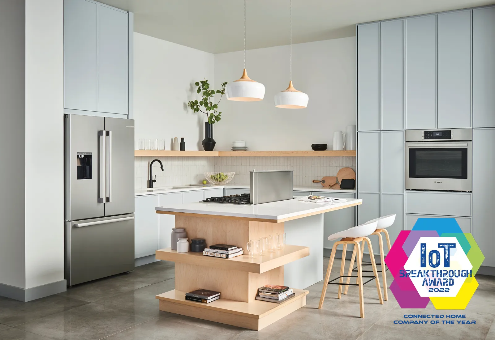 Modern kitchen featuring a Bosch stainless steel fridge, island with stove, and pendant lighting.