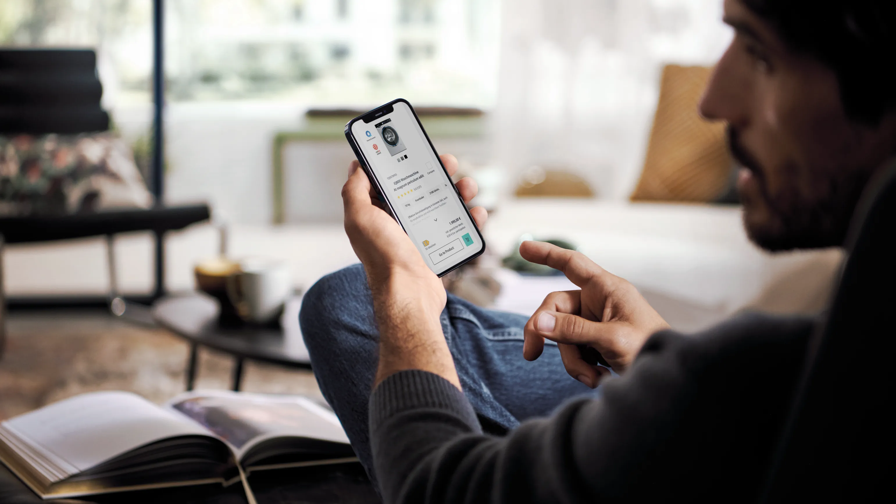 Osoba używająca smartfona podczas czytania książki na kanapie w salonie.