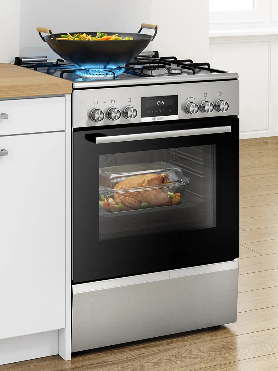 Bosch kitchen with stacked black ovens built into white cabinetry, next to a window.
