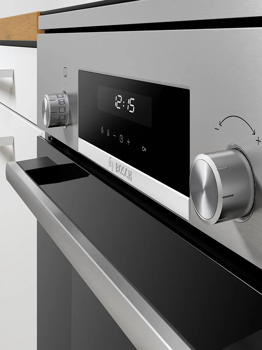 Close-up of a stainless-steel freestanding Bosch oven: brushed-metal control panel with two rotary knobs, a black digital display showing "12:15," the Bosch logo, and a partially open black-glass oven door beneath a wooden countertop edge.