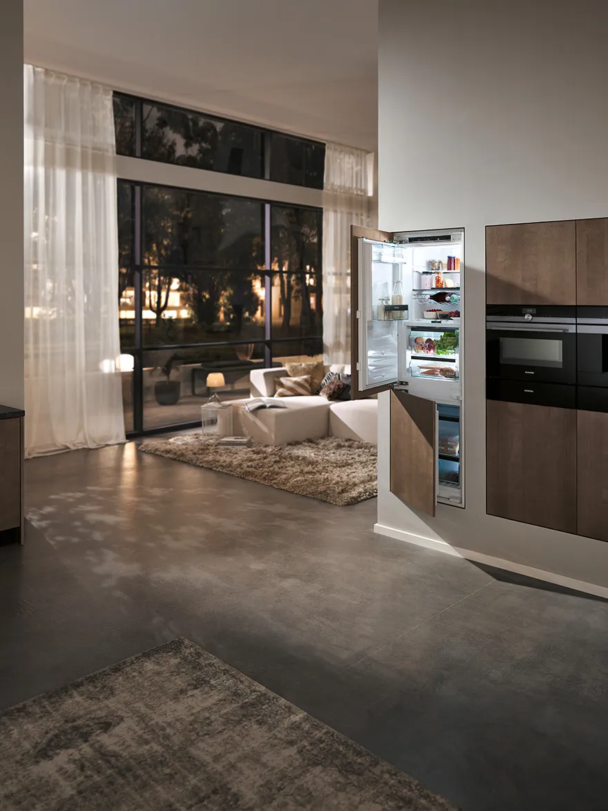 Un réfrigérateur Siemens encastré avec des façades en bois assorties aux meubles d’une cuisine moderne.