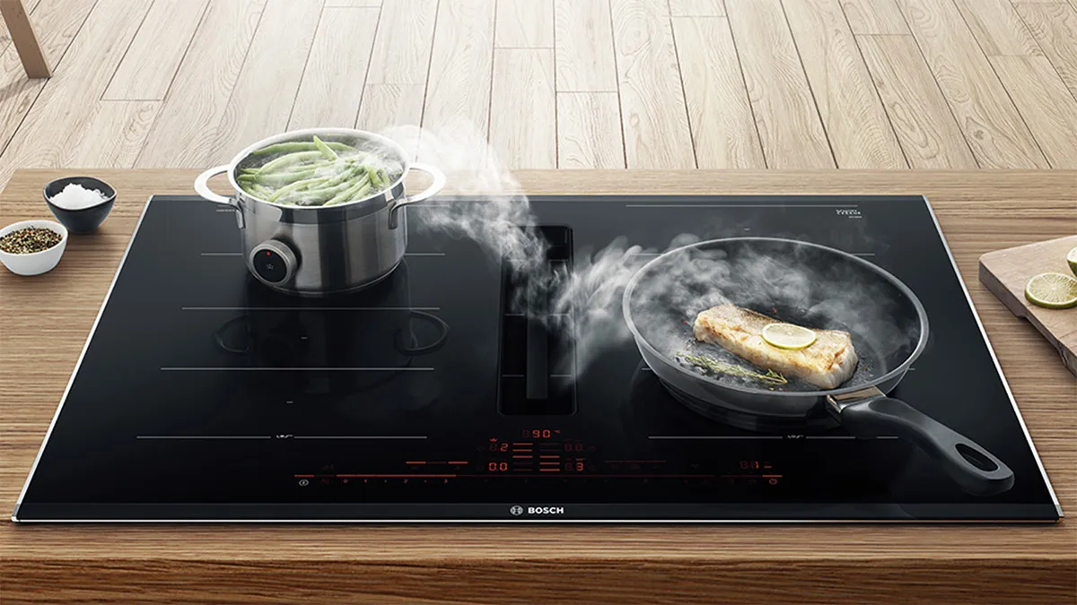 Steam rises from a pan and pot on a modern induction cooktop.