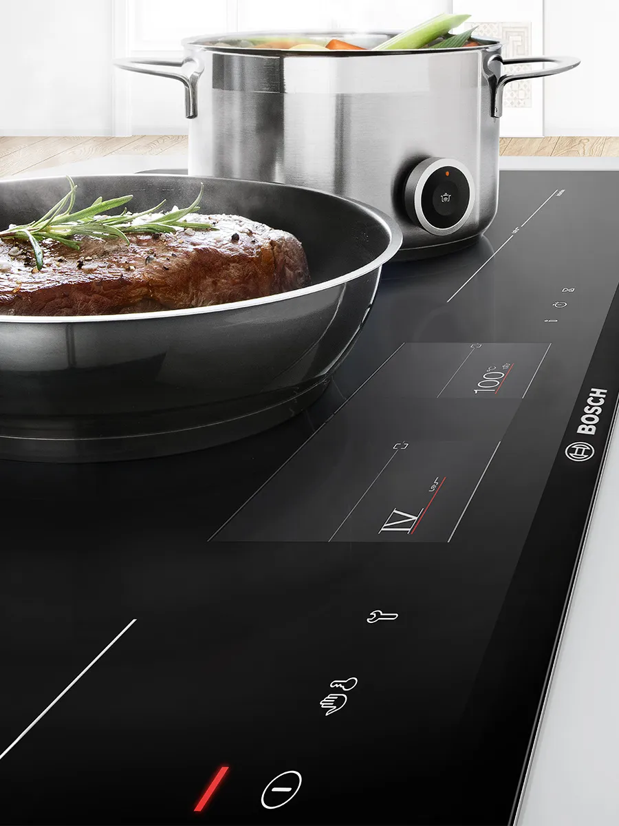 Cucina moderna con cappa a soffitto in acciaio inox sopra un'isola di legno.