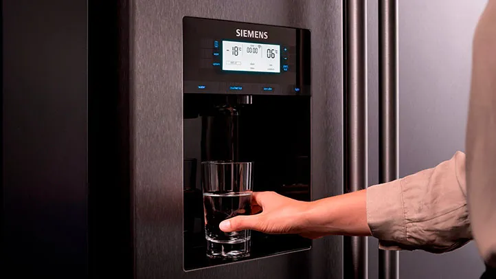 Jemand bedient den Eiswürfelspender einer Siemens French Door Kühl-Gefrierkombination