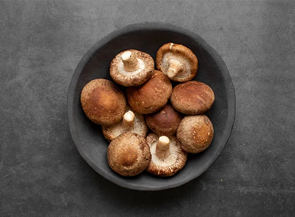 Plate of various mushrooms, including brown and white varieties, on a dark background.