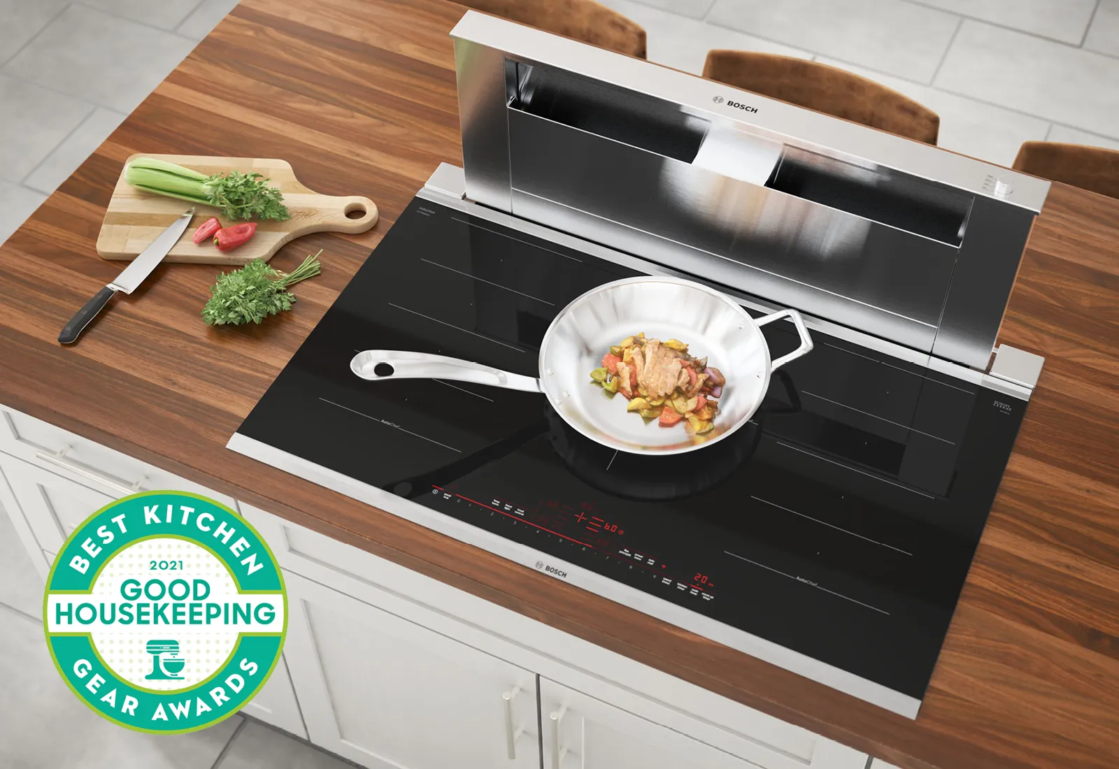 Bosch Induction cooktop with a saucepan frying vegetables, award sticker on a wooden counter.