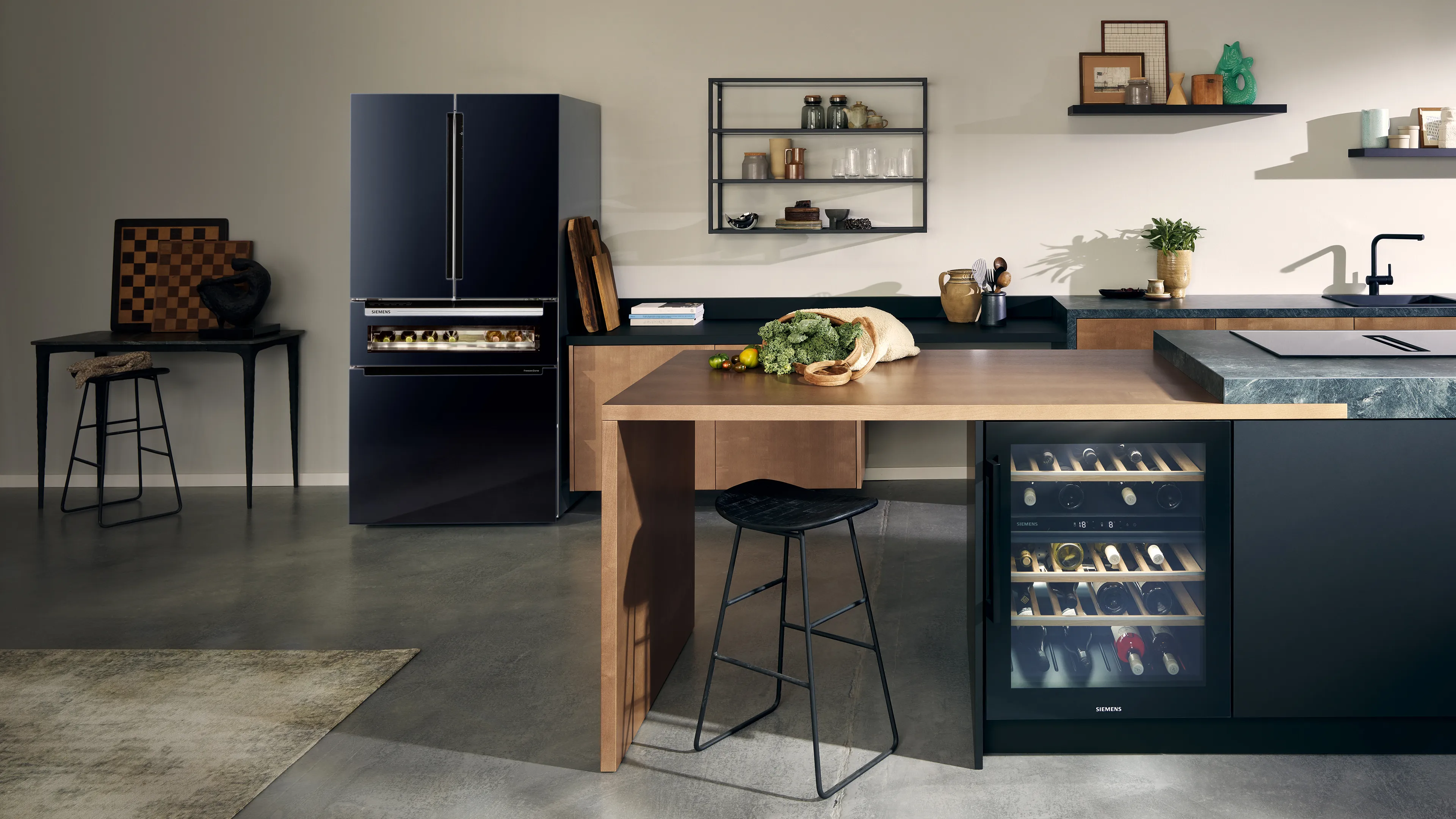 Moderna cocina en tonos oscuros en la que destaca un frigorífico multi-puerta de gran capacidad en color negro y una vinoteca bajo encimera de Siemens.
