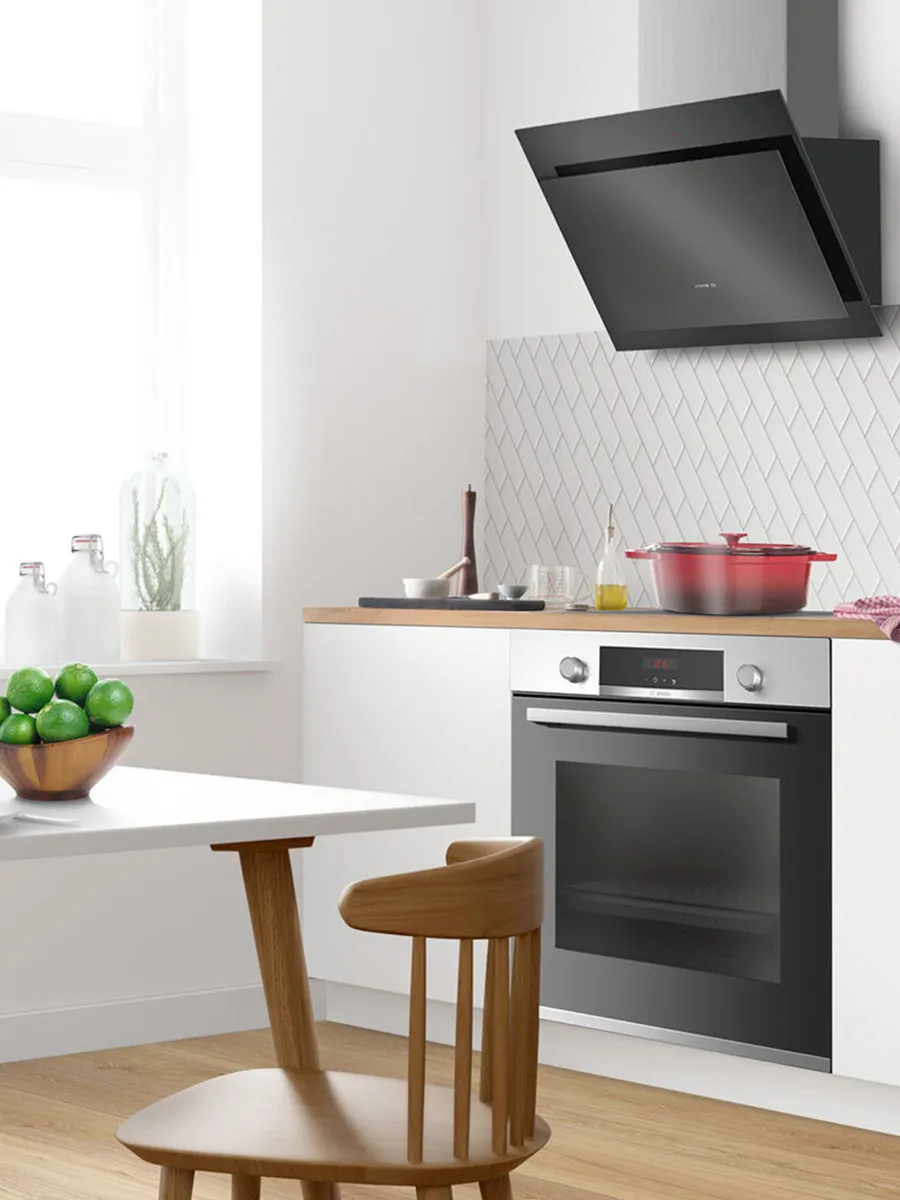 A person holds a smartphone displaying a smart appliance app in a modern kitchen.