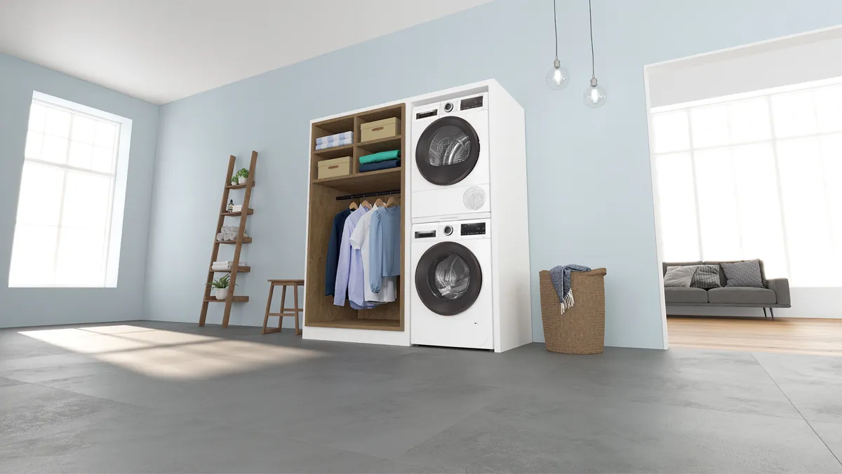 Stacked washer and dryer integrated into a white cabinet with a laundry basket on top.