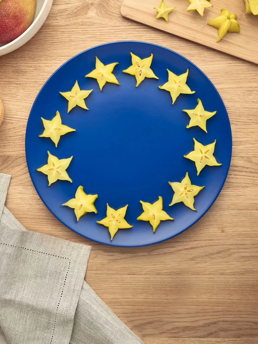 Slices of yellow star fruit on a blue plate create a representation of the European flag.