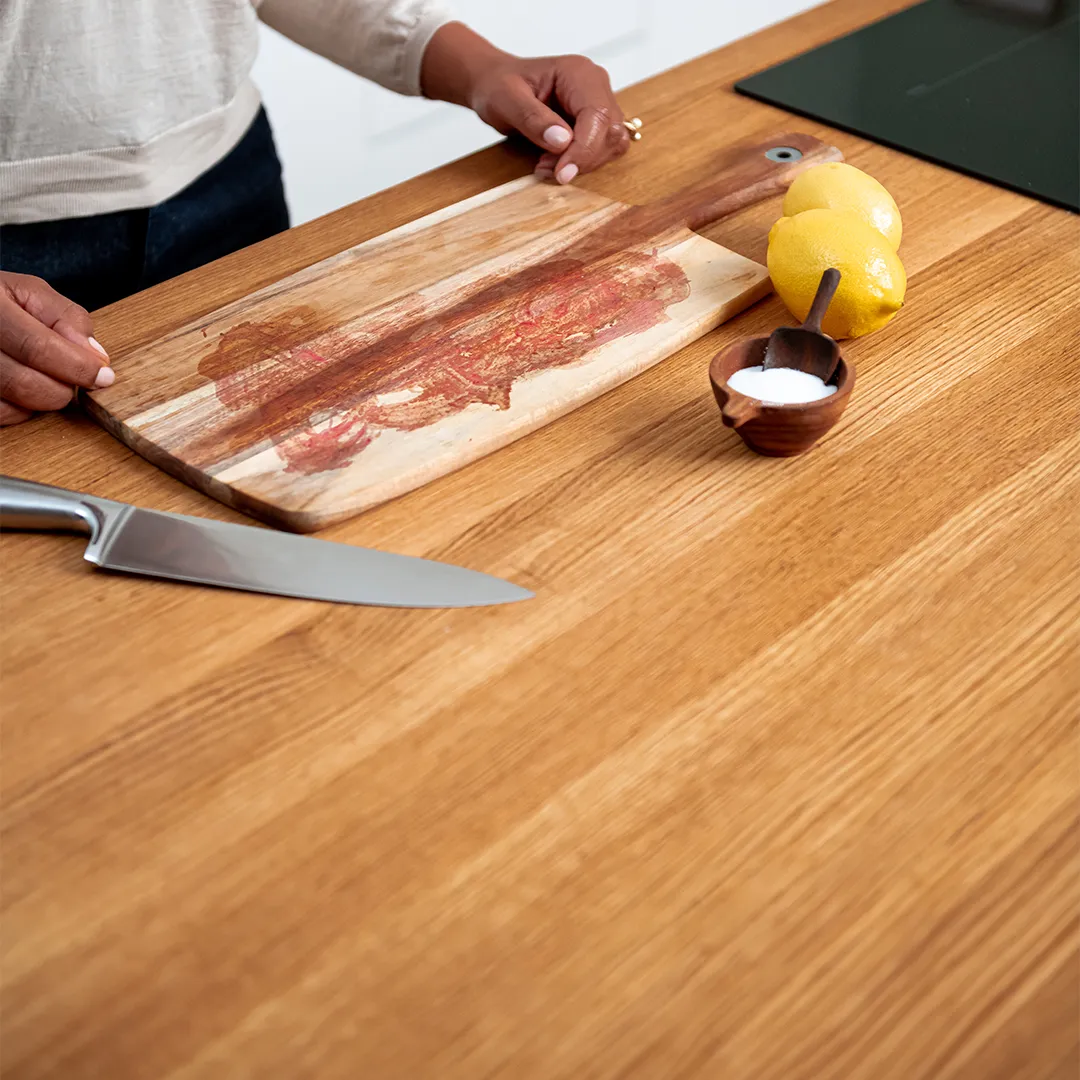 Wood countertop with a cutting board, knife, lemons, and bowl of salt.