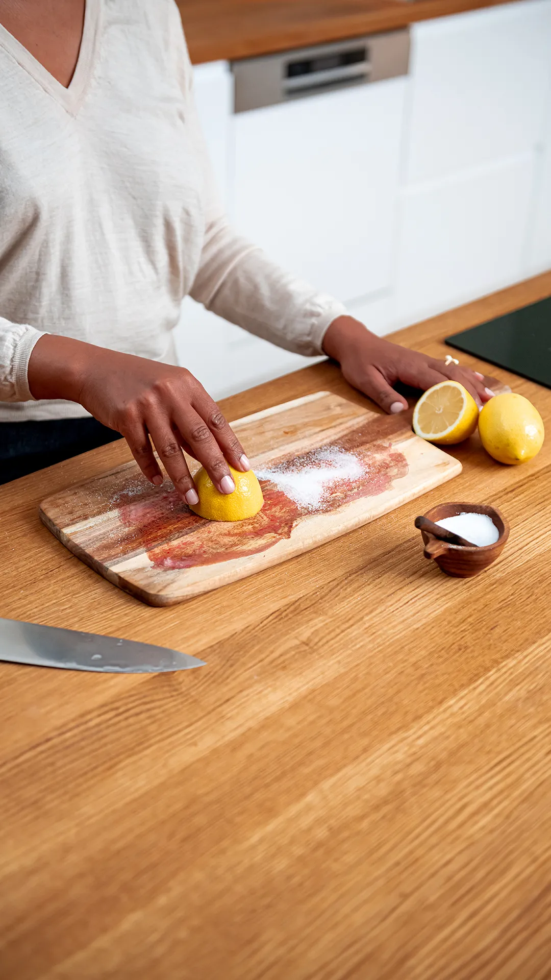 Grandma cleaning a wooden cutting board using lemon and salt