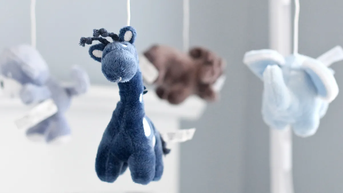 Mjuka plyschleksaker som hänger från mobilen, inklusive en blå giraff och andra fuzzy djur.