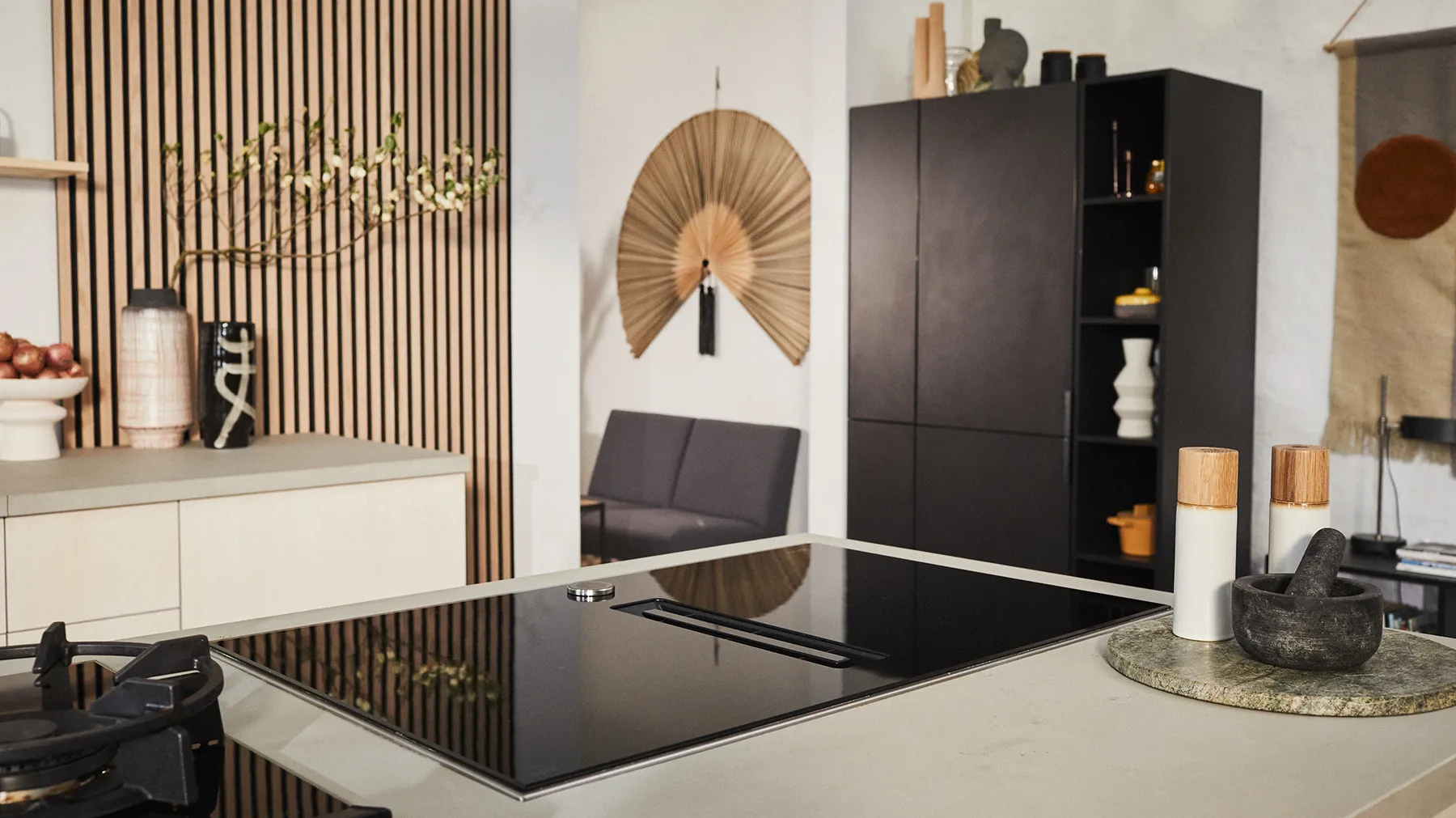 Moderne Küche im Japandi-Stil mit Kochinsel, schwarzer Sitzbank, Holzlamellenwand und dekorativem Wandfächer
