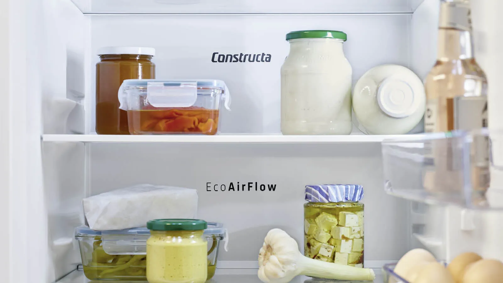 Blick in einen Constructa Kühlschrank mit EcoAirflow. Diverse Lebensmittel sind auf den Ablagen sichtbar.