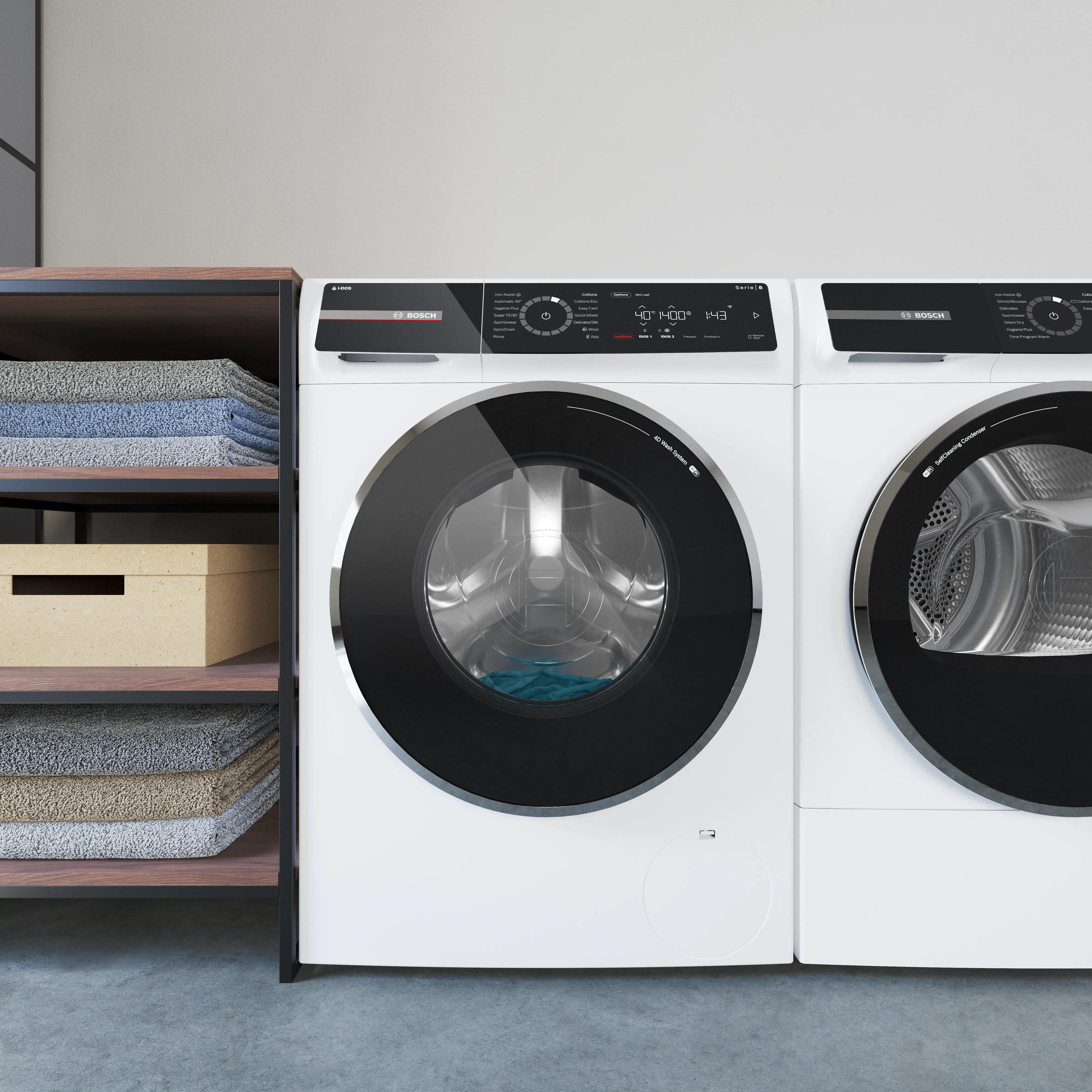 White front-load washer and dryer set in a laundry room, showing a blue garment inside the glass drum next to a wooden shelf.