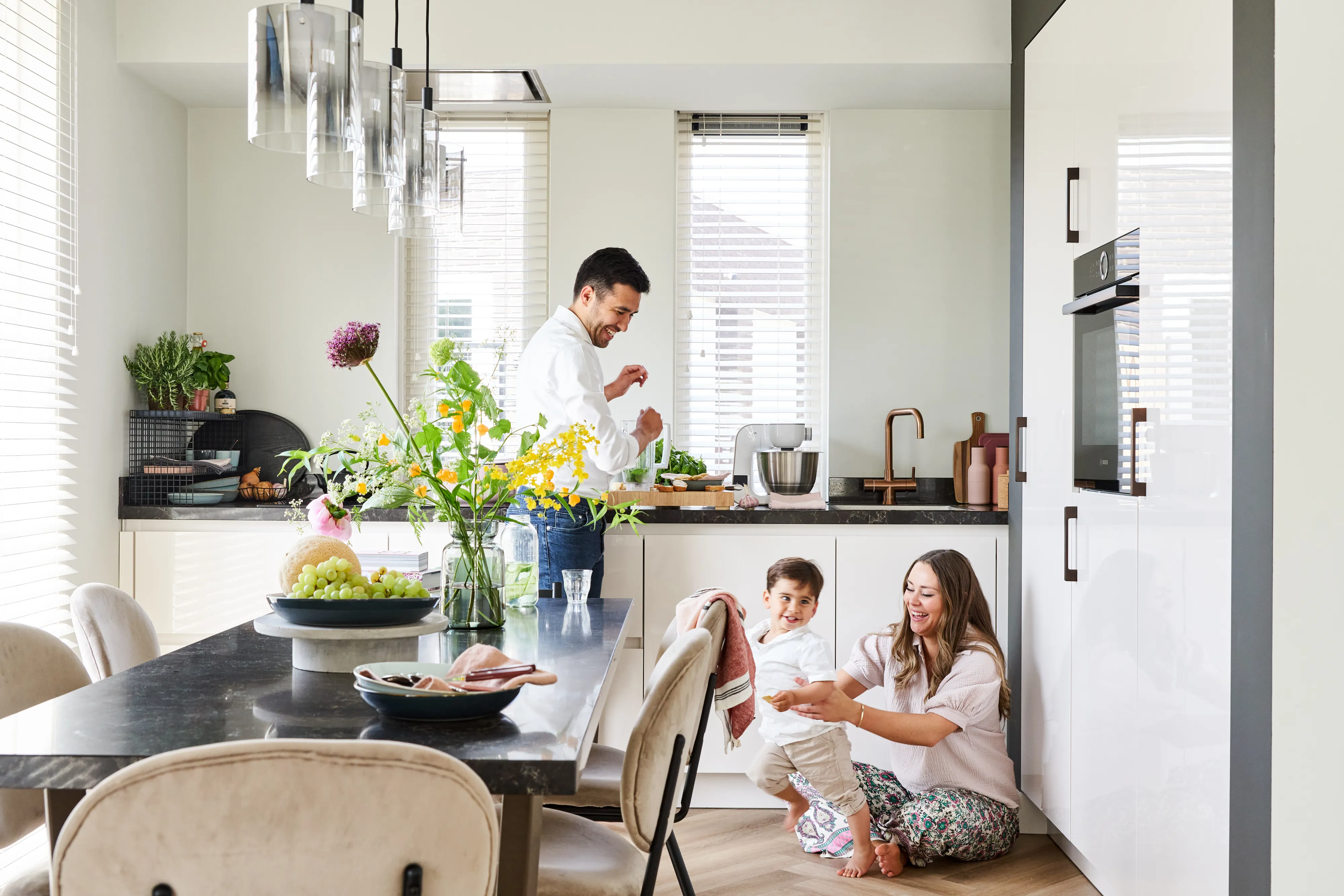 Cuisine familiale dans une cuisine moderne avec des fleurs, table à manger et lumière naturelle.