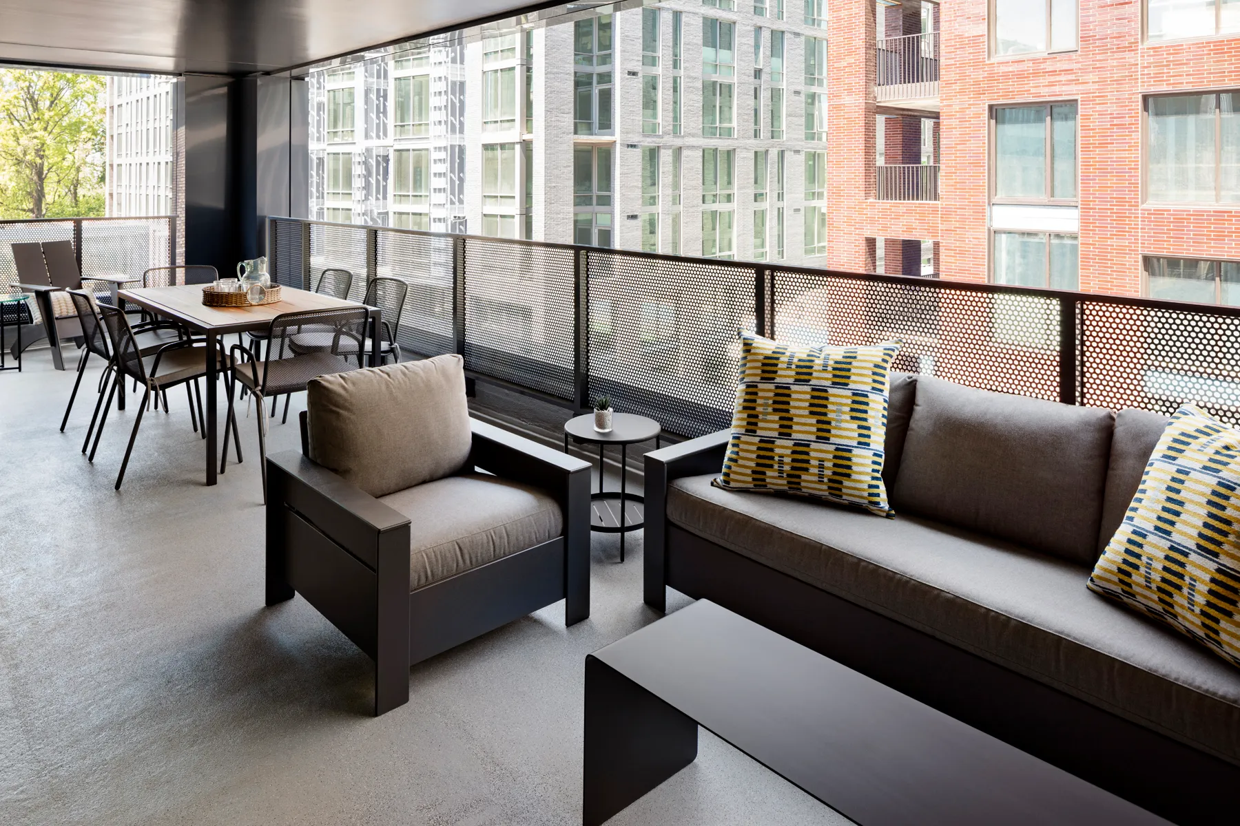 Modern balcony with brown furniture, patterned cushions, and a dining table set for four.