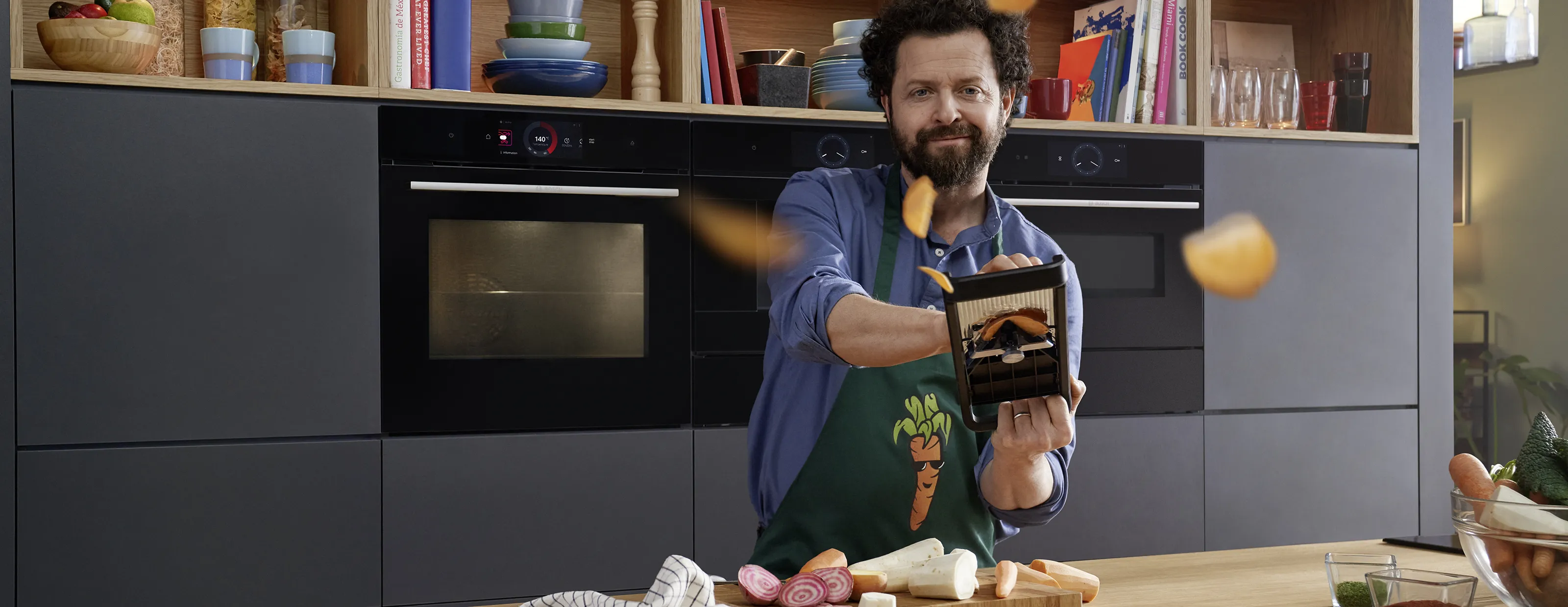Człowiek w kuchni gotowania, trzymający naczynia kuchenne, otoczony sprzętem kuchennym i półkami.