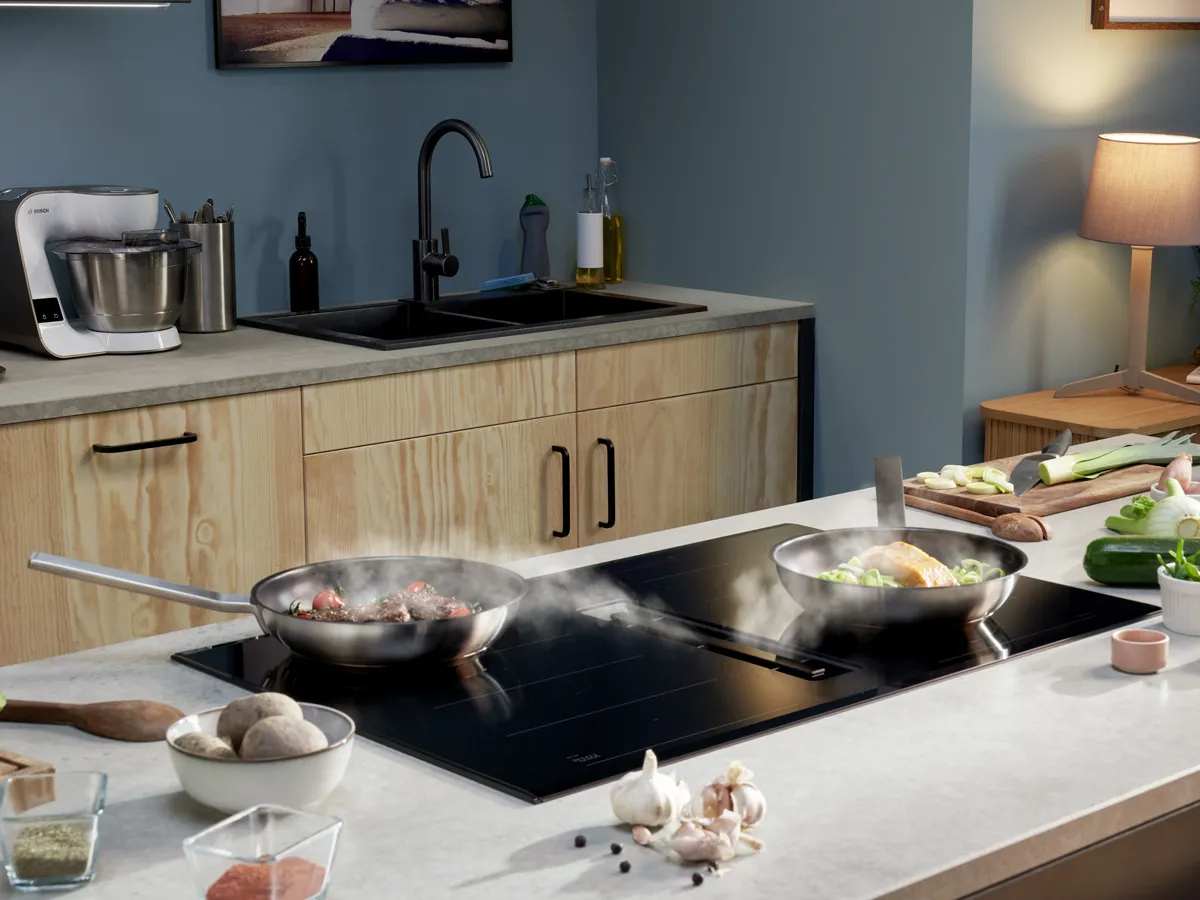 Modern kitchen with cooking appliances, utensils, and ingredients on countertop.