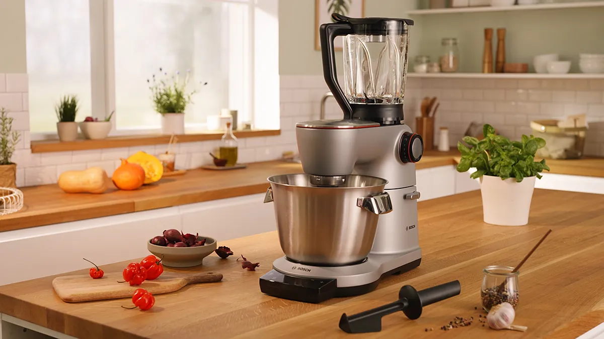 Kitchen countertop with food prep tools, including a stand mixer, cutting board, and fresh produce.