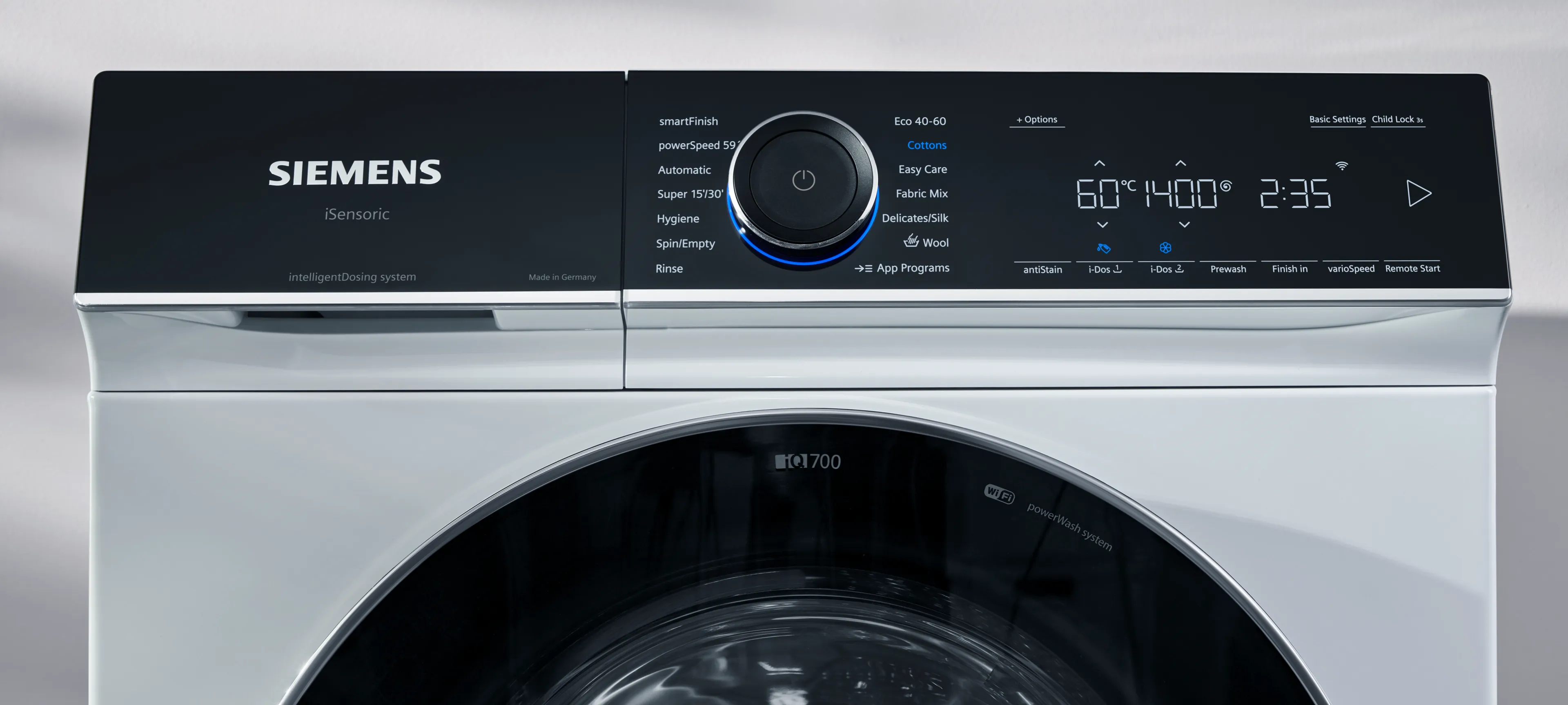 Siemens washing machine with open door, displaying clothes inside and control panel.