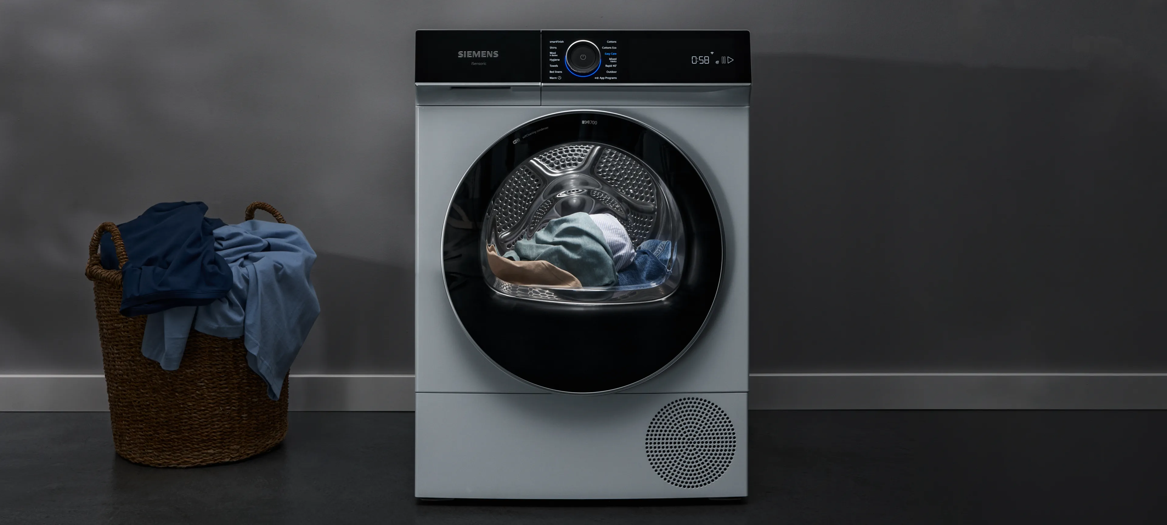 Siemens clothes dryer with digital display and open door revealing laundry inside.