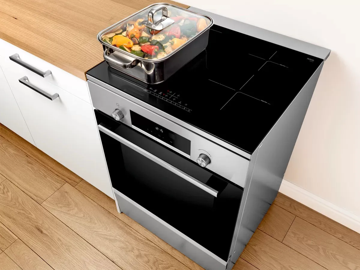 Bosch freestanding cooker with a gas hob cooking a wok dish and oven roasting chicken, combining versatility and style.