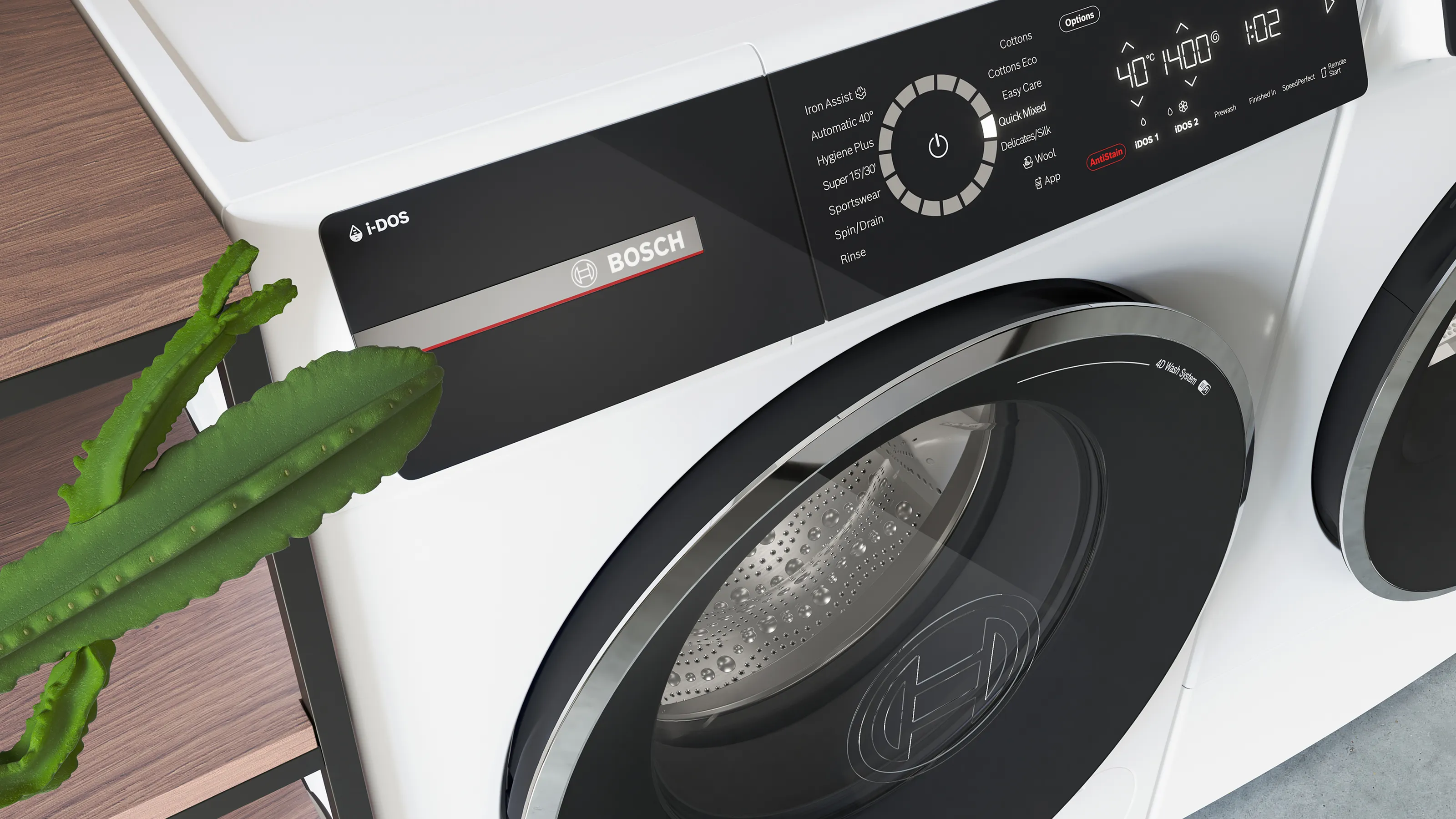 Zbliżenie na panel sterowania pralki Bosch z technologią i-DOS, na którym widać różne ustawienia oraz cyfrowy wyświetlacz pokazujący temperaturę i pozostały czas. Na górze pralki znajduje się roślina w doniczce, a widać także bęben w otworze z logo Bosch
