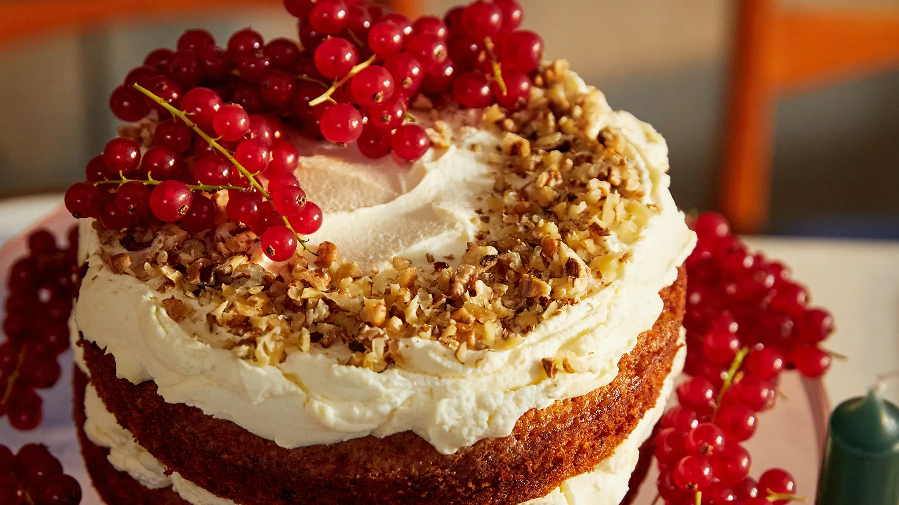 Layered cake with whipped cream, crunchy topping, and vibrant red currants.
