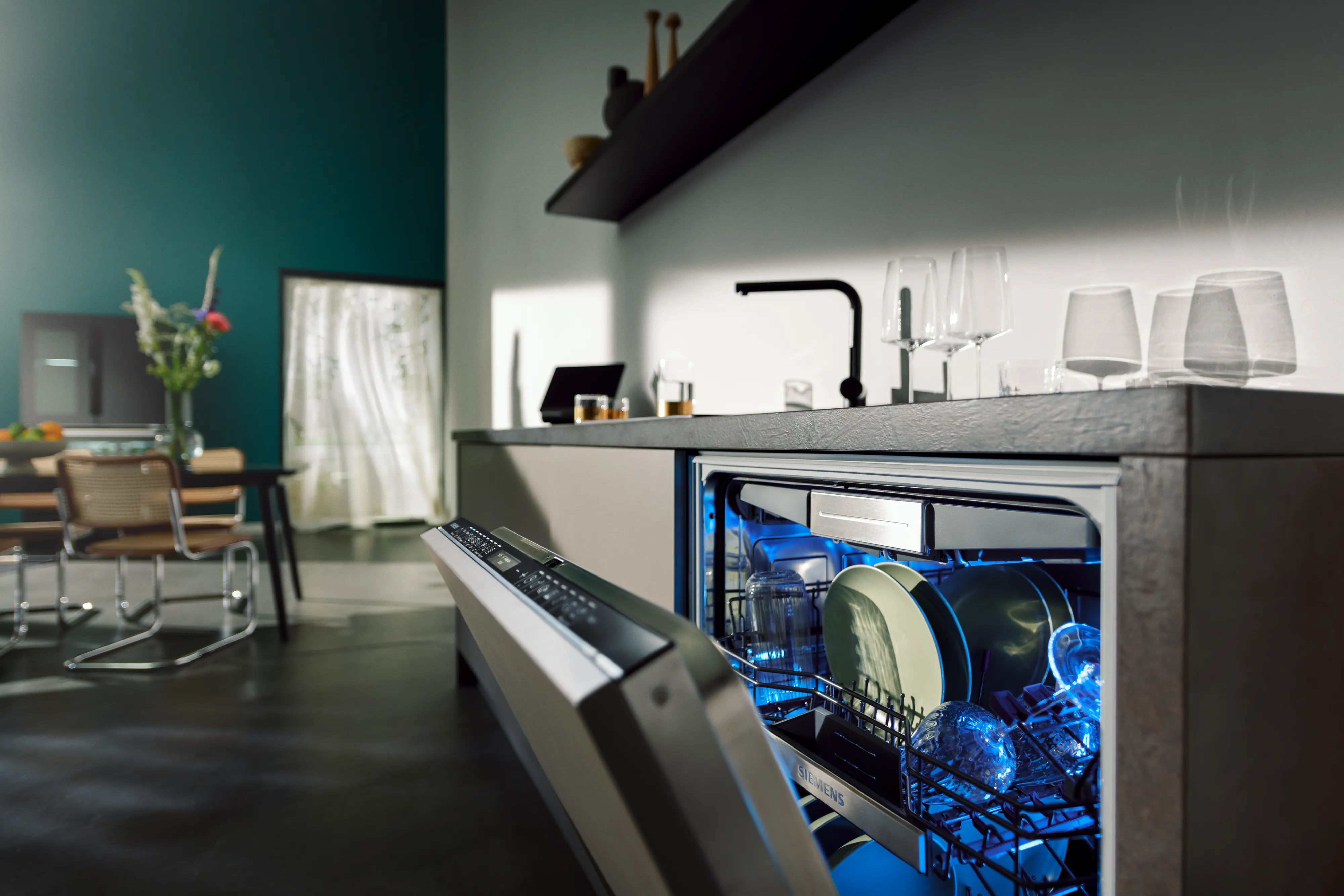 Moderne keuken met open vaatwasser, keukenapparatuur en eethoek zichtbaar.