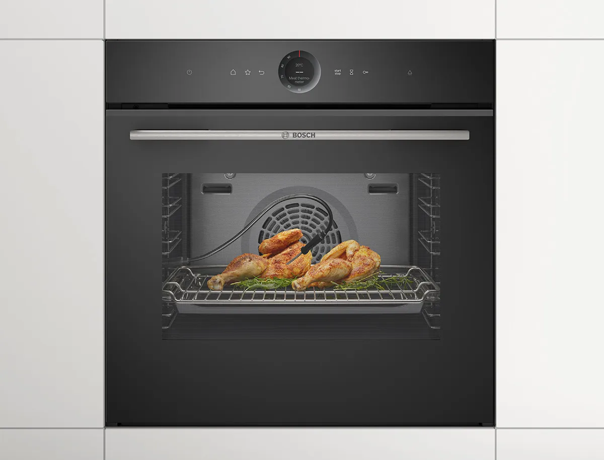 A chicken roasting in an oven with a meat probe monitoring the temperature.