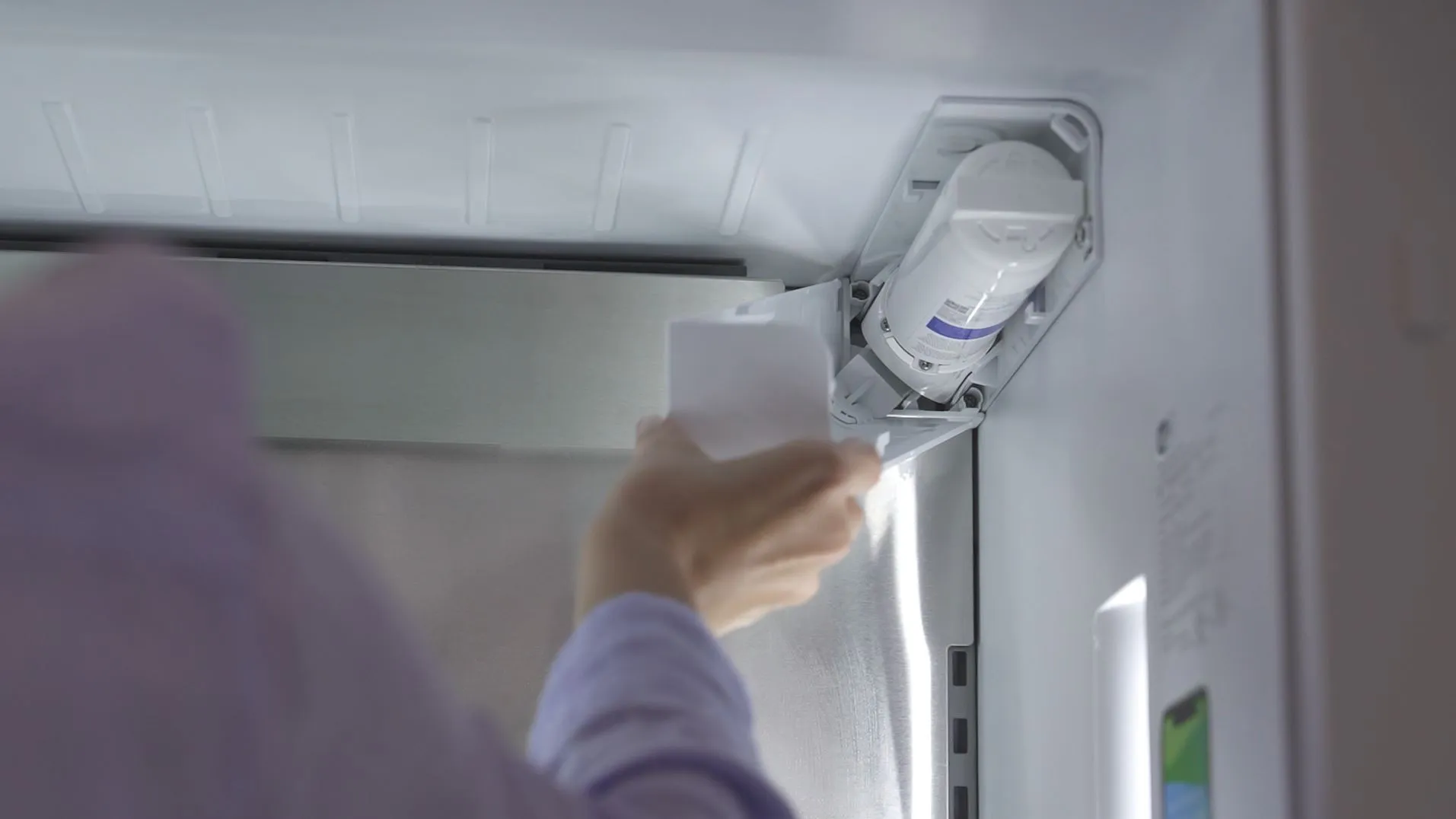 Person opening Bosch refrigerator door, revealing interior with various food items and installing water filter