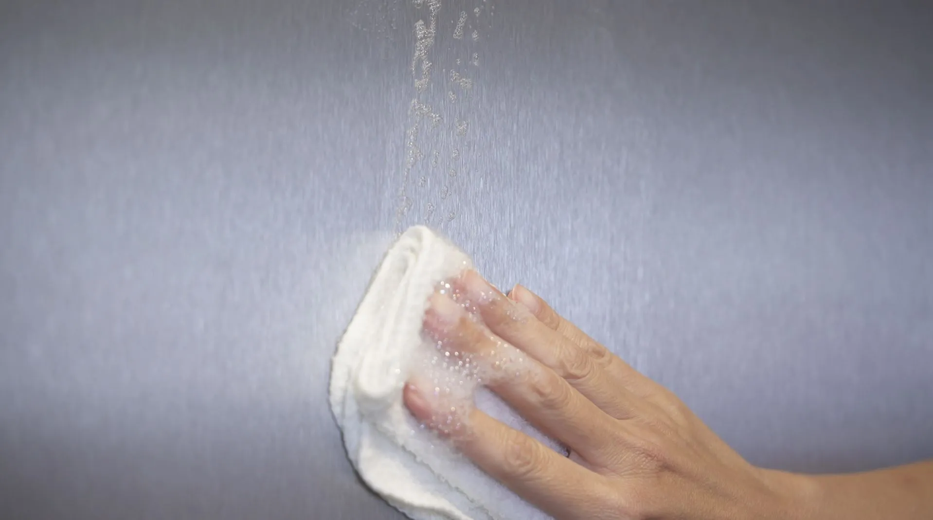 Hands wiping a wet, foggy surface, creating a clear spot.