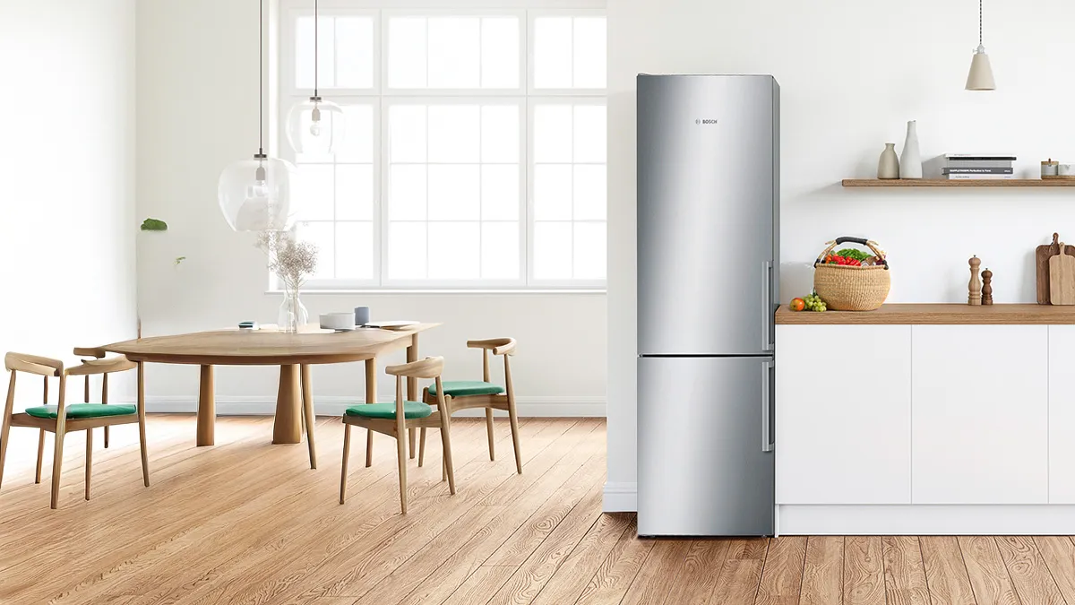 Helle, moderne Küche mit silbernem Kühlschrank, Holzmöbeln und Regalen mit Küchenutensilien.