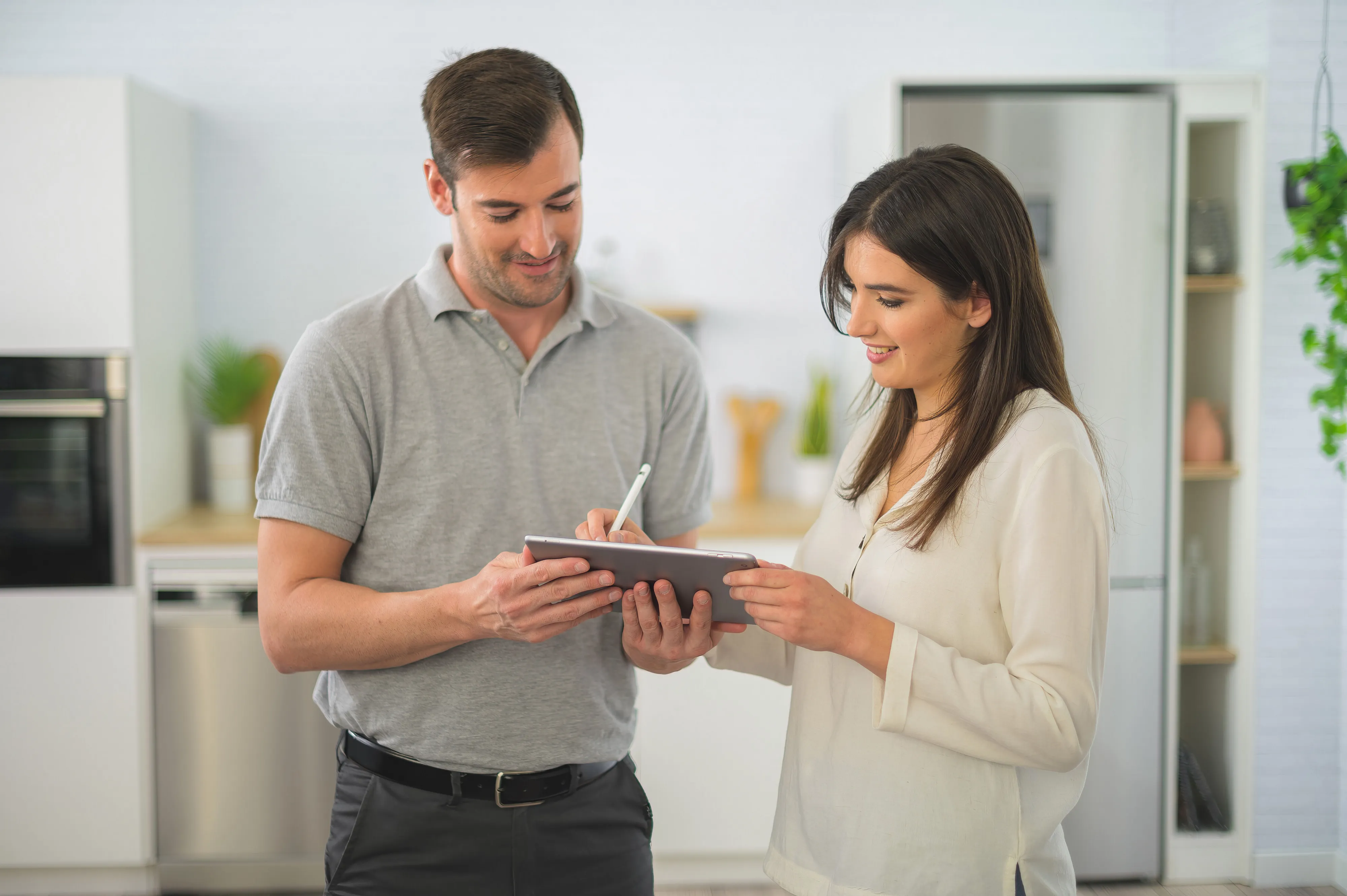 Mutfakta dijital tablet kullanıyor, gülümseyerek ve konuşmaya çalışıyor.